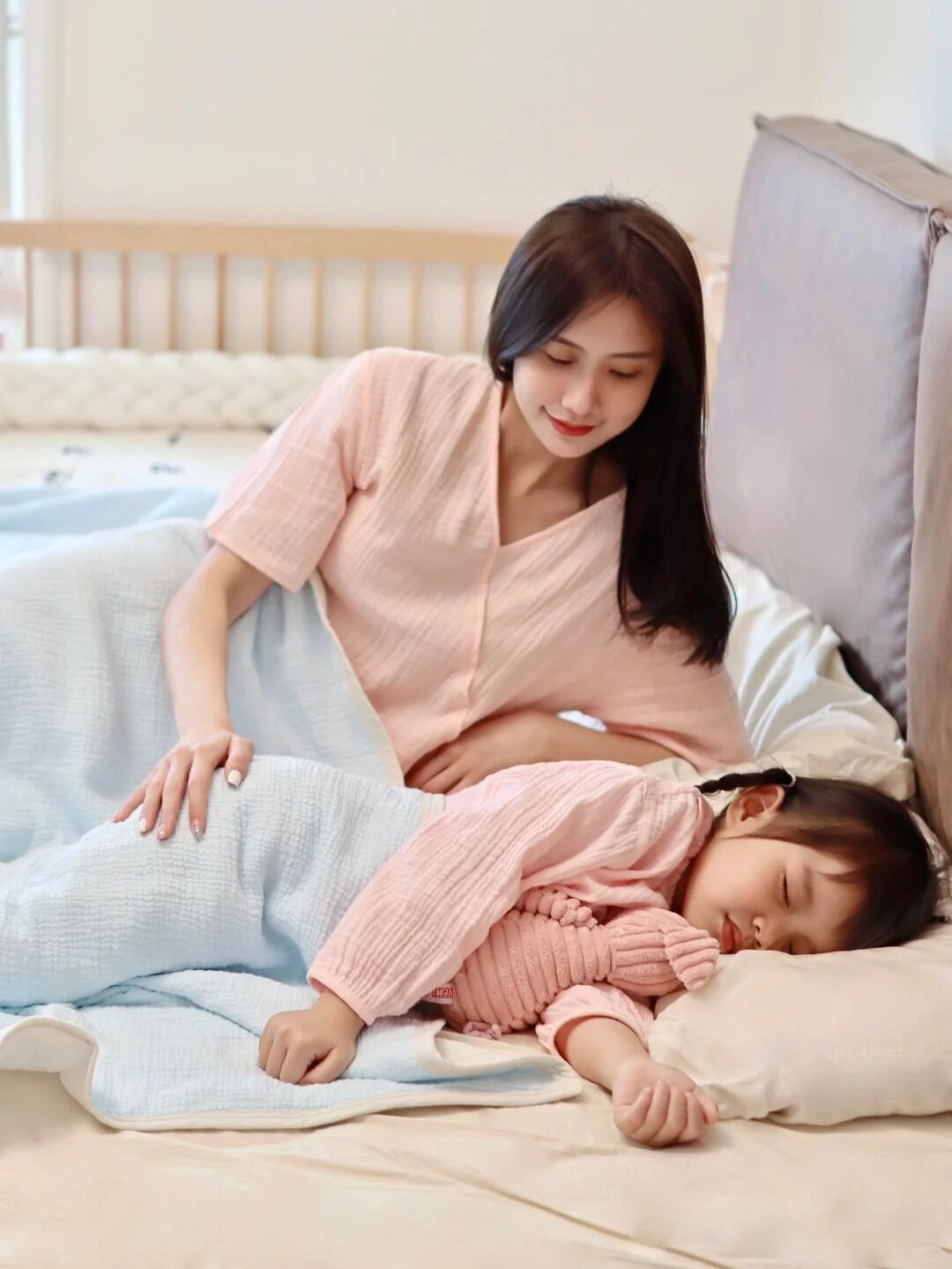 Bé ôm thú bông khi ngủ, mẹ dịu dàng vuốt ve đầy yêu thương.