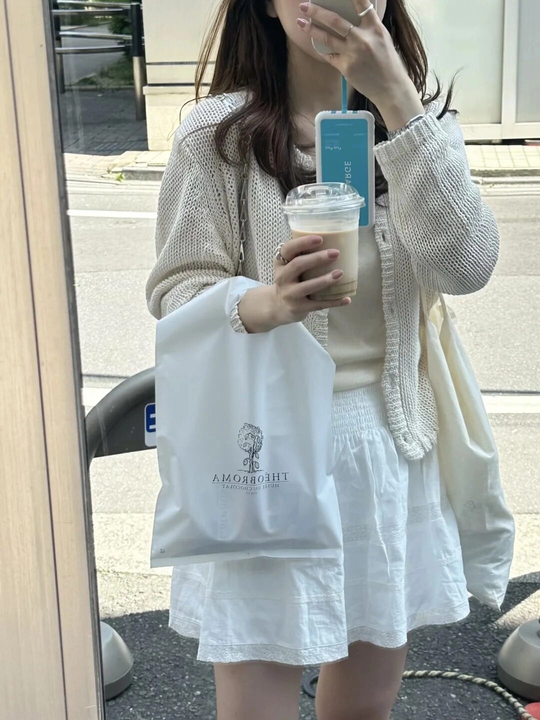 Tay cầm ly cà phê, trang phục nhẹ nhàng khi selfie trước gương.