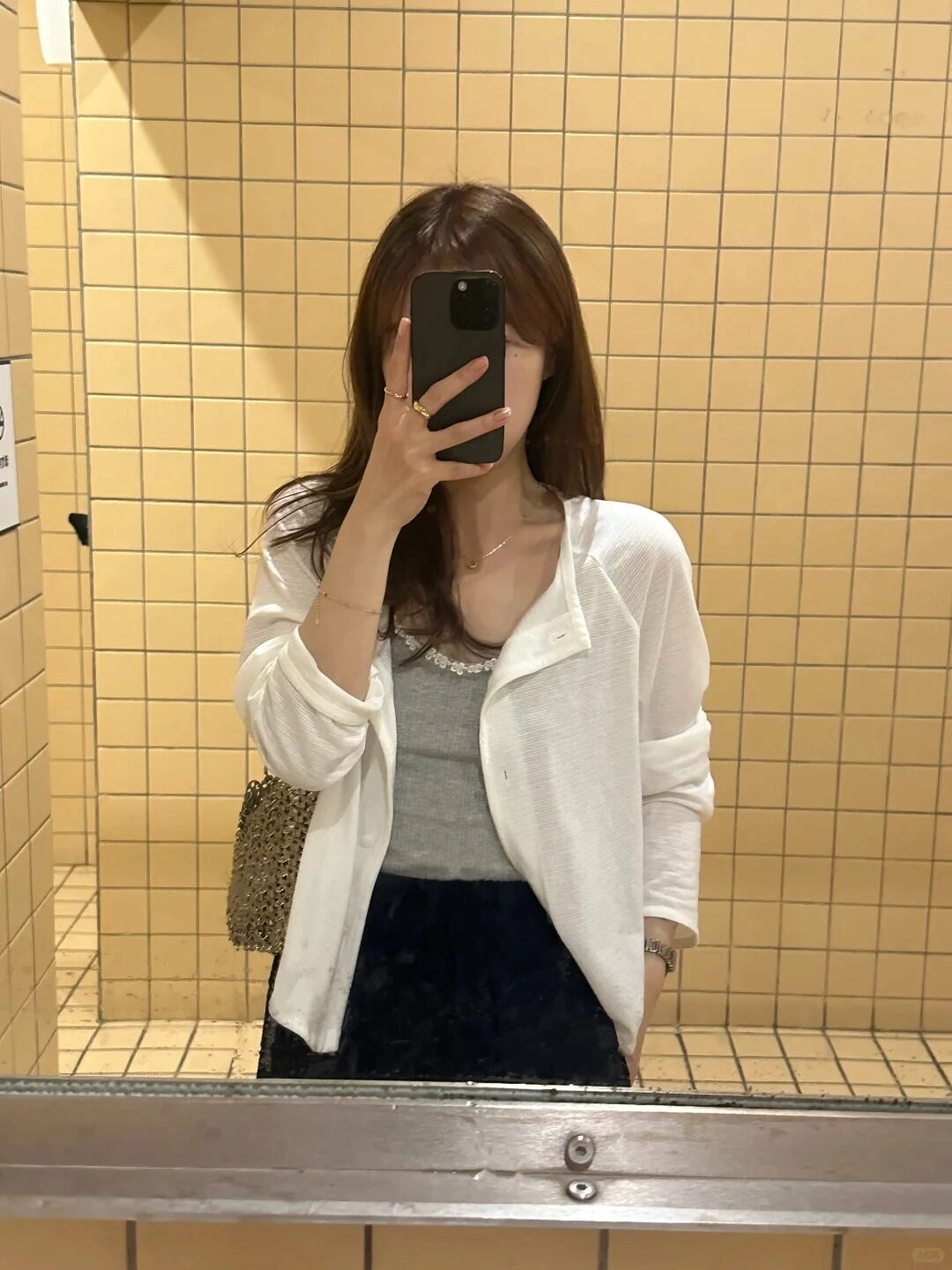 Tóc xõa ngang vai, mặc áo cardigan bên ngoài áo xám thanh lịch.