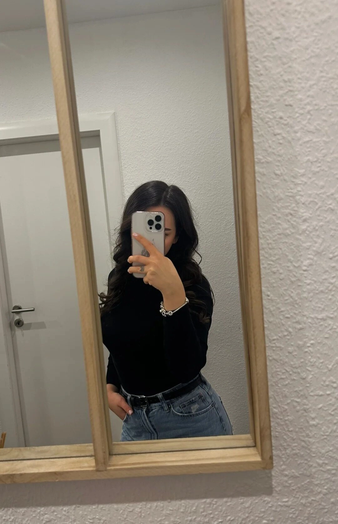 Tóc xoăn dài, áo phức quần jeans năng động chụp trước ống kính.