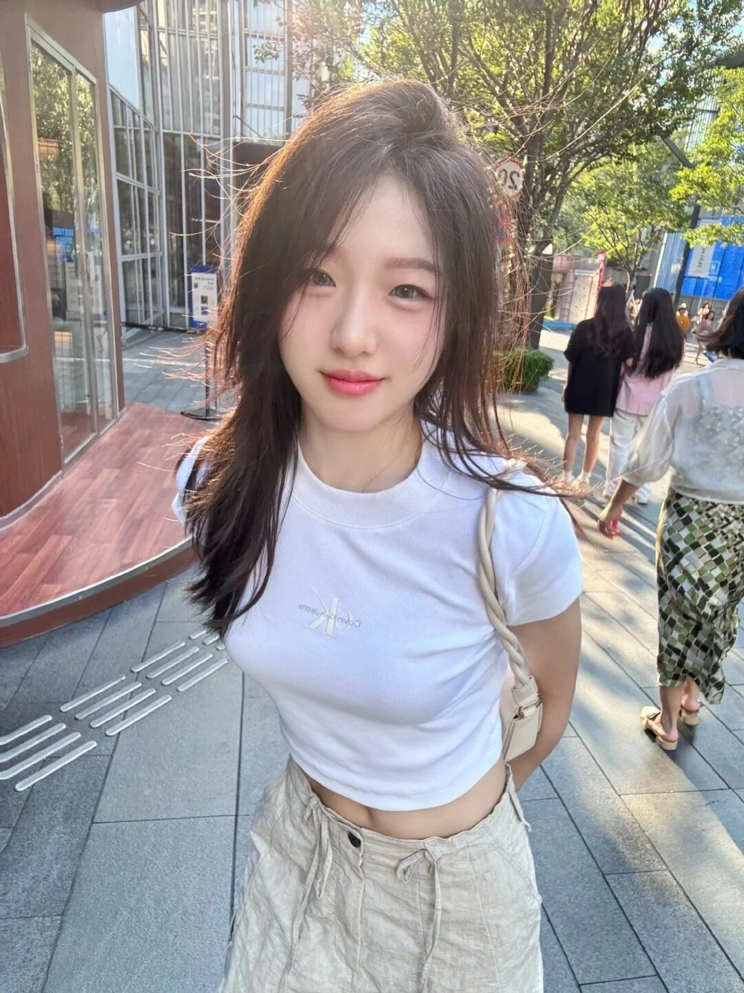 Bạn trẻ 2k10 xuống phố, mái tóc dài bồng bềnh, áo croptop trắng năng động.