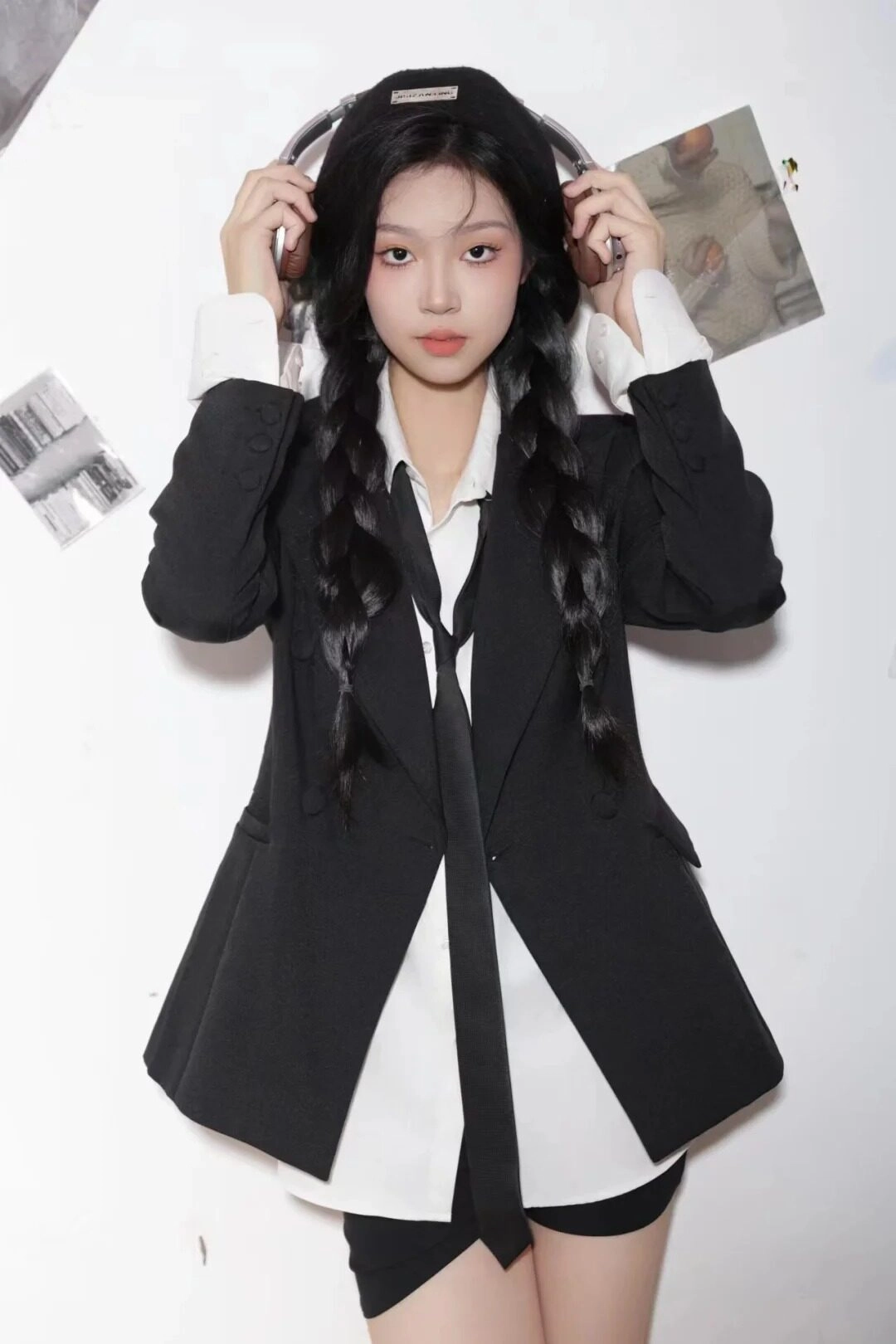 Thiếu nữ phong cách cá tính, mặc vest đen, thắt cà vạt, vương tai nghệ.