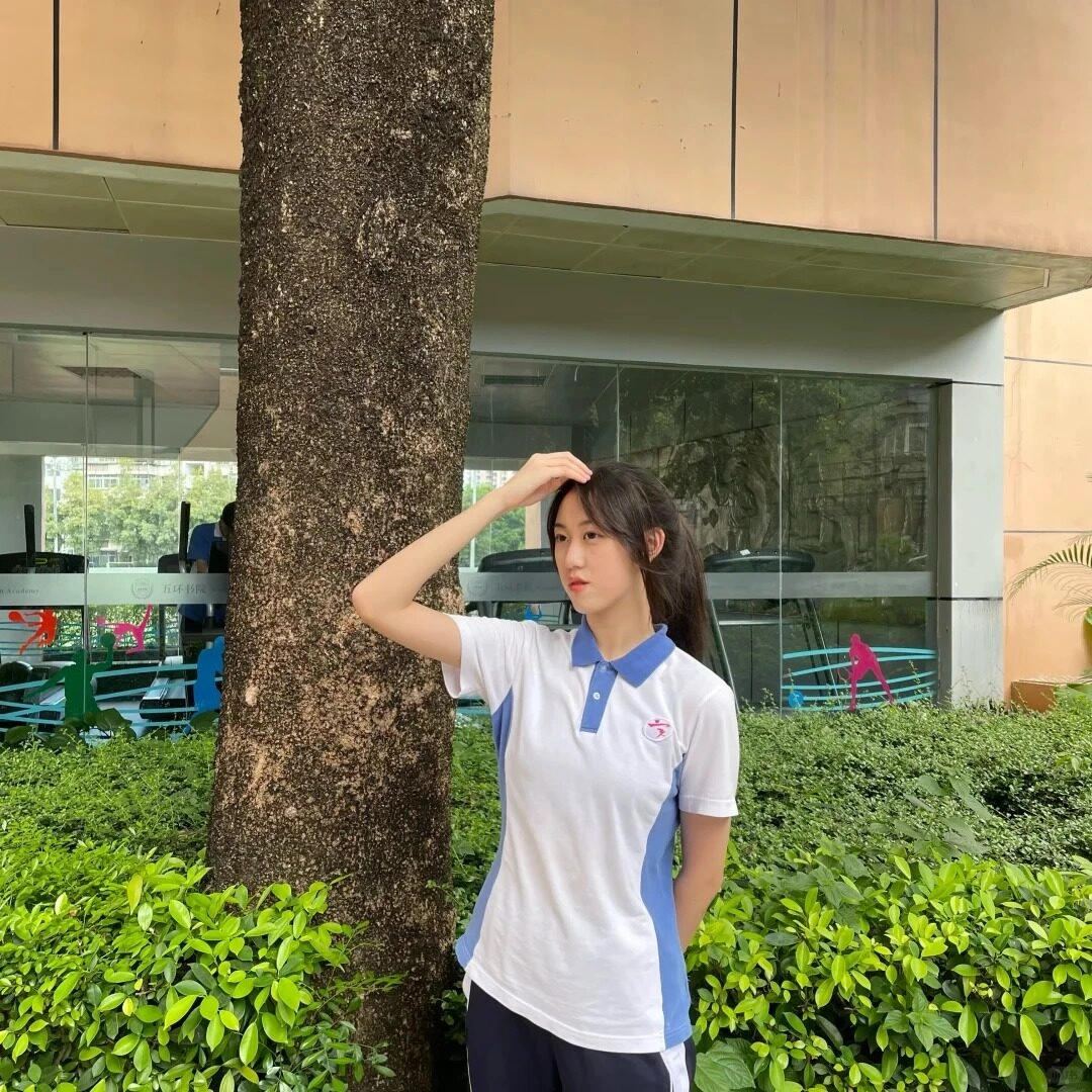 Bên gốc cây xanh mát, cô gái trong bộ thể thao đơn giản nhưng năng động.