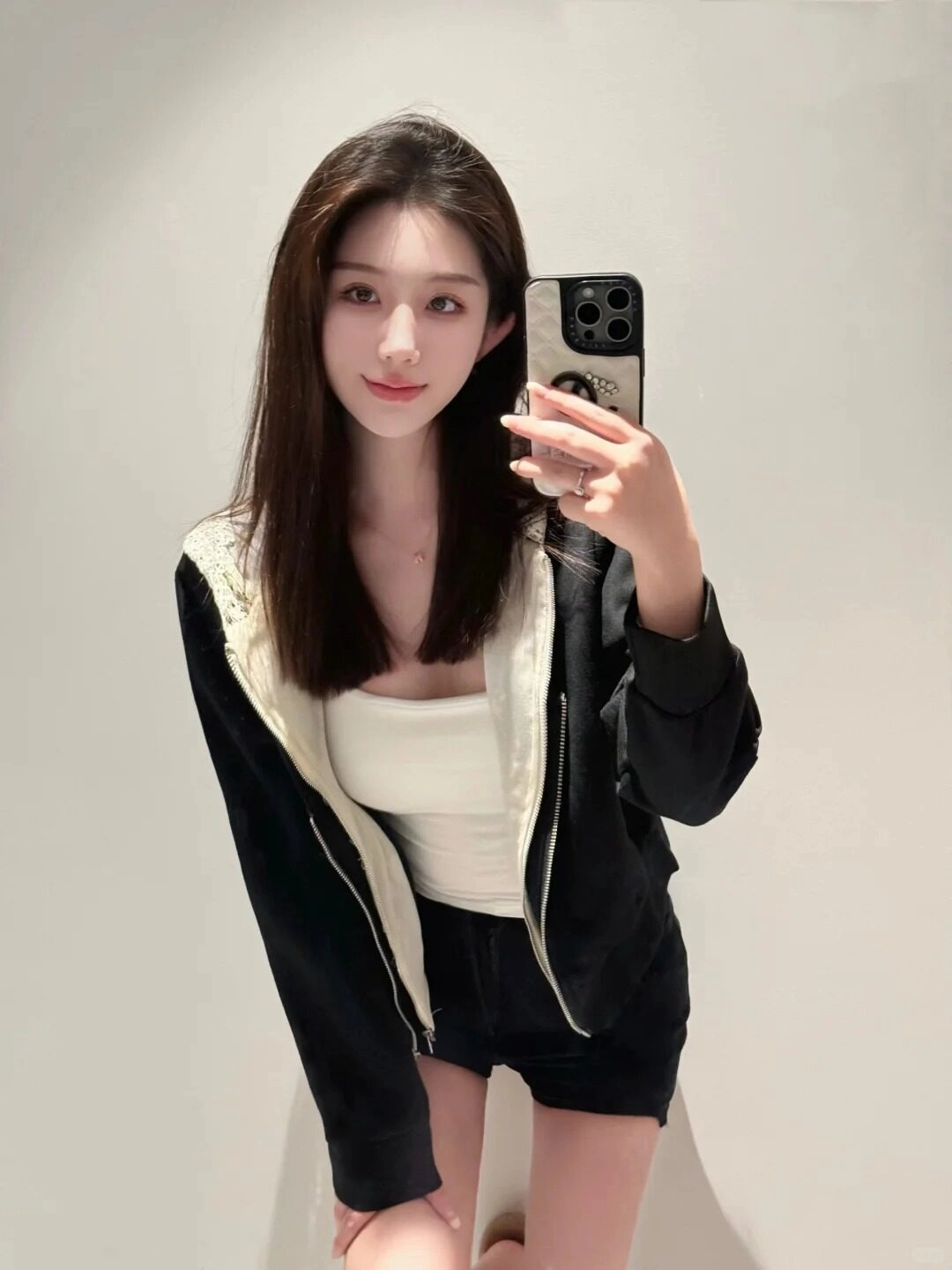 Cười nhẹ nhàng, mái tóc thẳng, áo khoác đen trắng năng động.