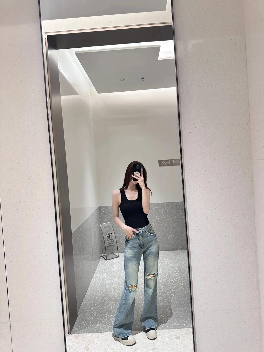 Quần jean rách gối, áo đen bó tạo kiểu dáng mát mẻ trước ống kính.