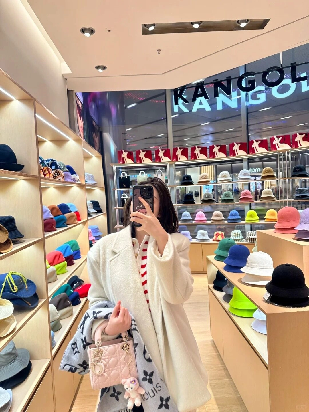 Áo khoác dài trắng sang trọng, chụp ảnh trong cửa hàng thời trang cao cấp.