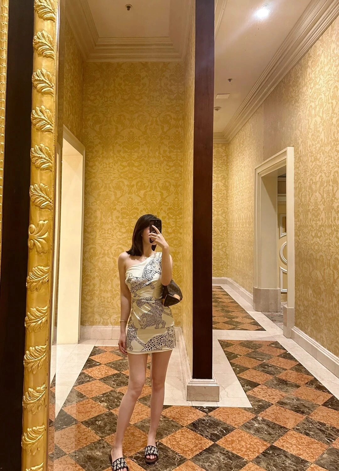 Váy ngắn trôi vai họa tiết báo cá tính, tạo kiểu dáng thanh lịch trước gương.