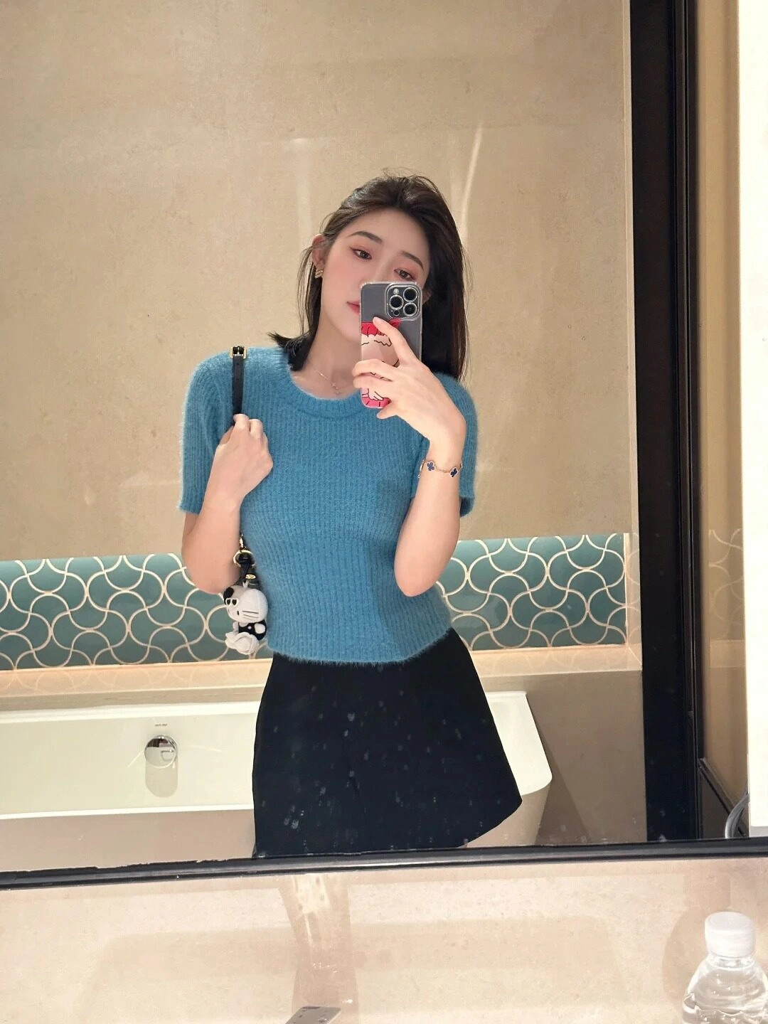 Áo len xanh ứng dụng phối váy đen đơn giản, tóc ngắn ngang vai trẻ trung.