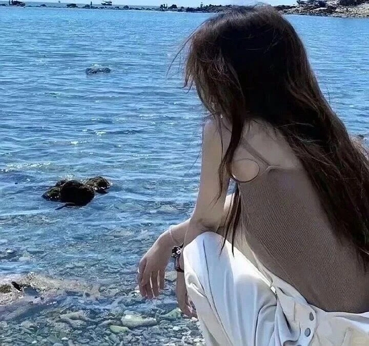  Ngồi bên bờ biển, mái tóc tung bay trong gió, diện áo len nâu nhẹ nhàng.