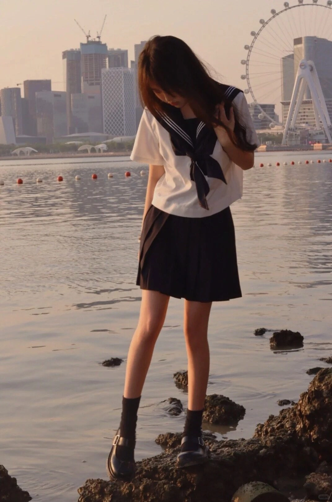 Cô nàng chăm chú ngắm nhìn đôi giày giữa hoàng hôn bên cạnh bờ biển.