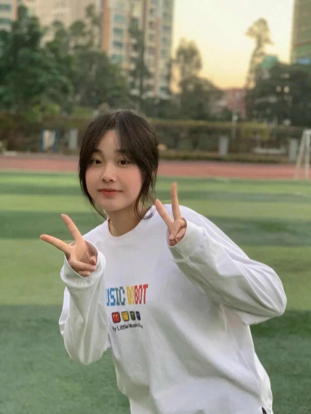 Tươi cười tinh nghịch và tạo dáng "peace" trên sân cỏ.