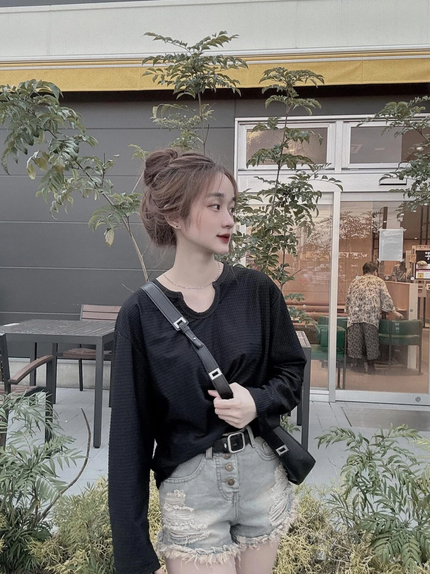 Áo len đen phối quần ngắn rách cùng tóc búi cao tạo vẻ đẹp năng động.