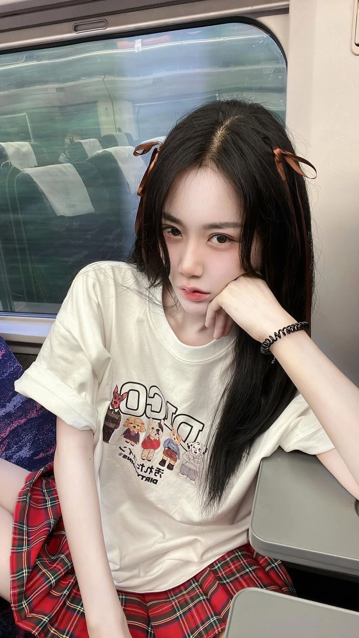 Thiếu nữa áo thun trắng váy kẻ đỏ, kiểu tóc nơ nâu đáng yêu và cá tính.