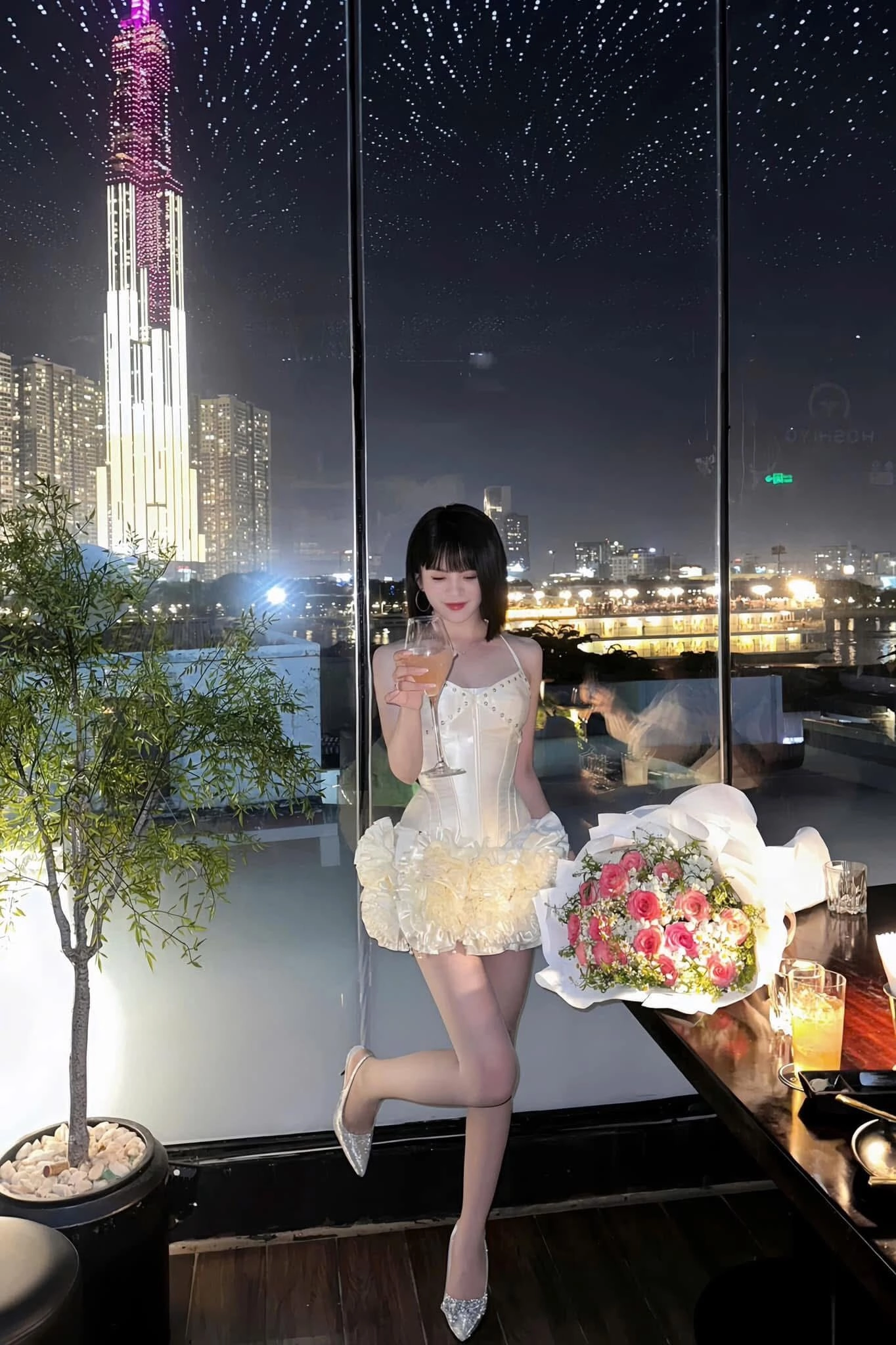 Đứng chill bên cửa kính, cầm ly nước và bó hoa xịn xò siêu to