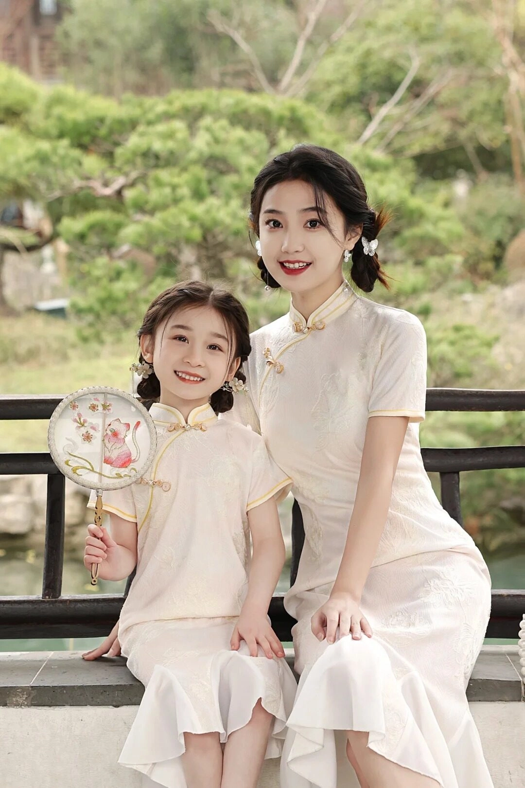 Hai mẹ con diện sườn xám trắng tinh khôi, nụ cười rạng rỡ giữa thiên nhiên.
