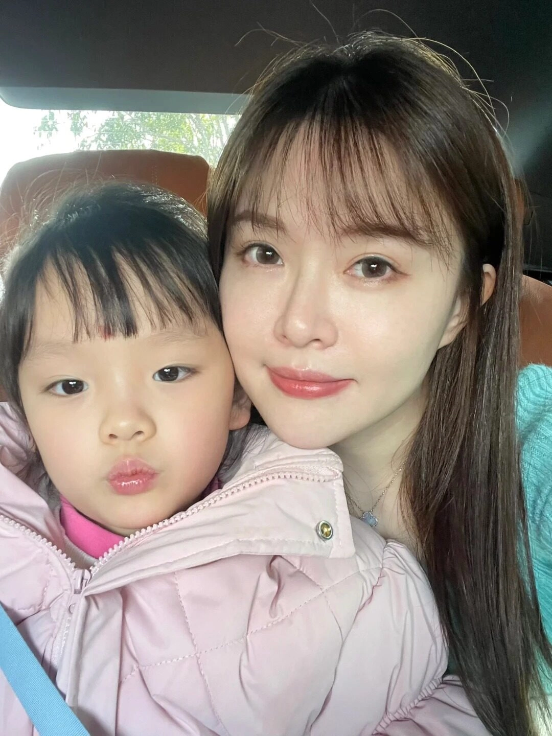 Mẹ mặc áo xanh nhạt, bé trong áo hồng bồng bềnh, cùng tạo dáng dễ thương.