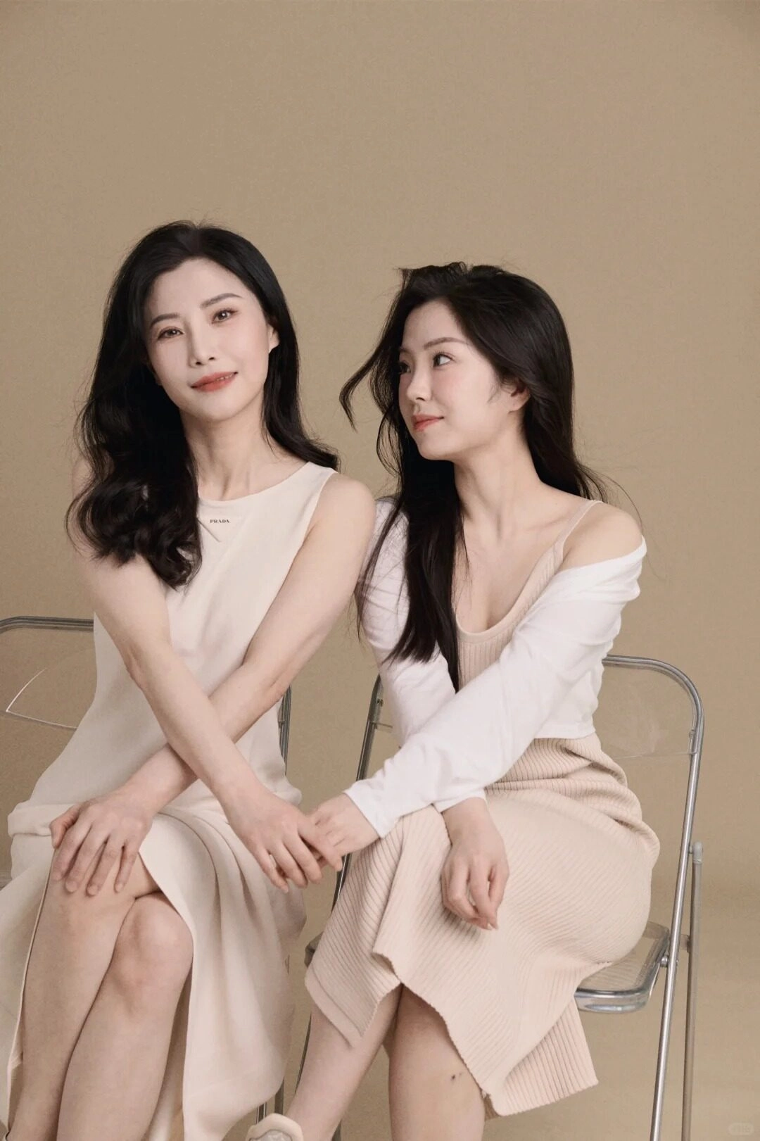 Mẹ và con gái trong bộ váy tông nude nhẹ nhàng, tay nắm chặt yêu thương.