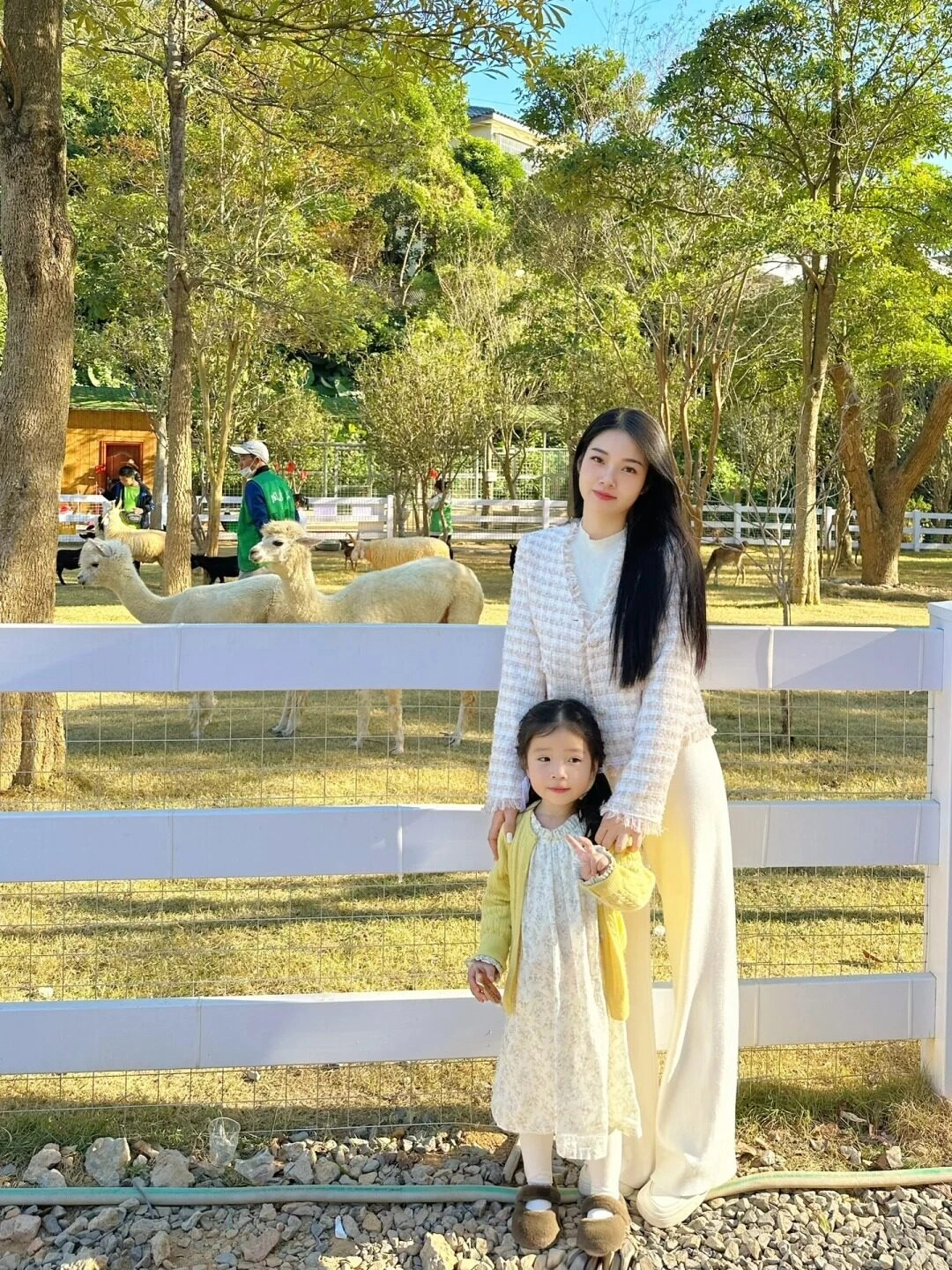 Mẹ và bé phối đồ trắng - vàng dịu dàng, nổi bật giữa khung cảnh đồng cỏ.
