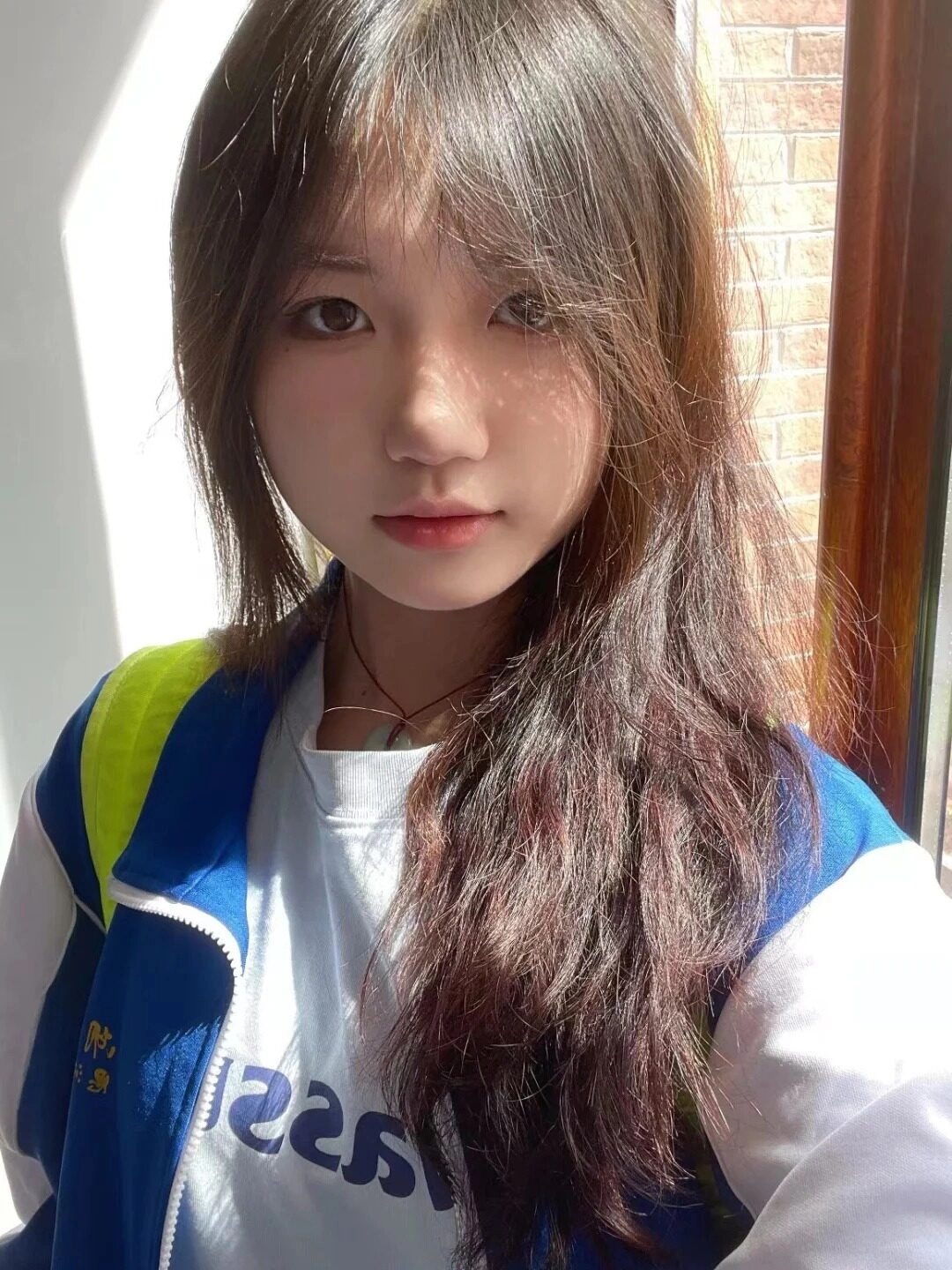 Áo khoác nữ sinh có thể có màu xanh trắng, mái tóc dài bồng bềnh dưới nắng nhẹ.