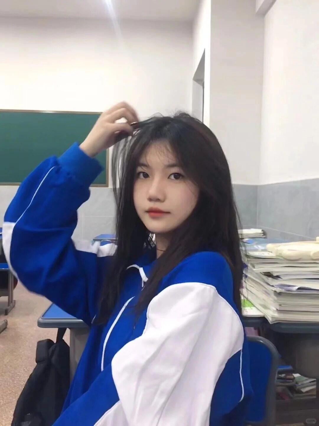 Cô gái vuốt tóc nhẹ nhàng trong chiếc áo khoác có thể thao tác trắng năng động.