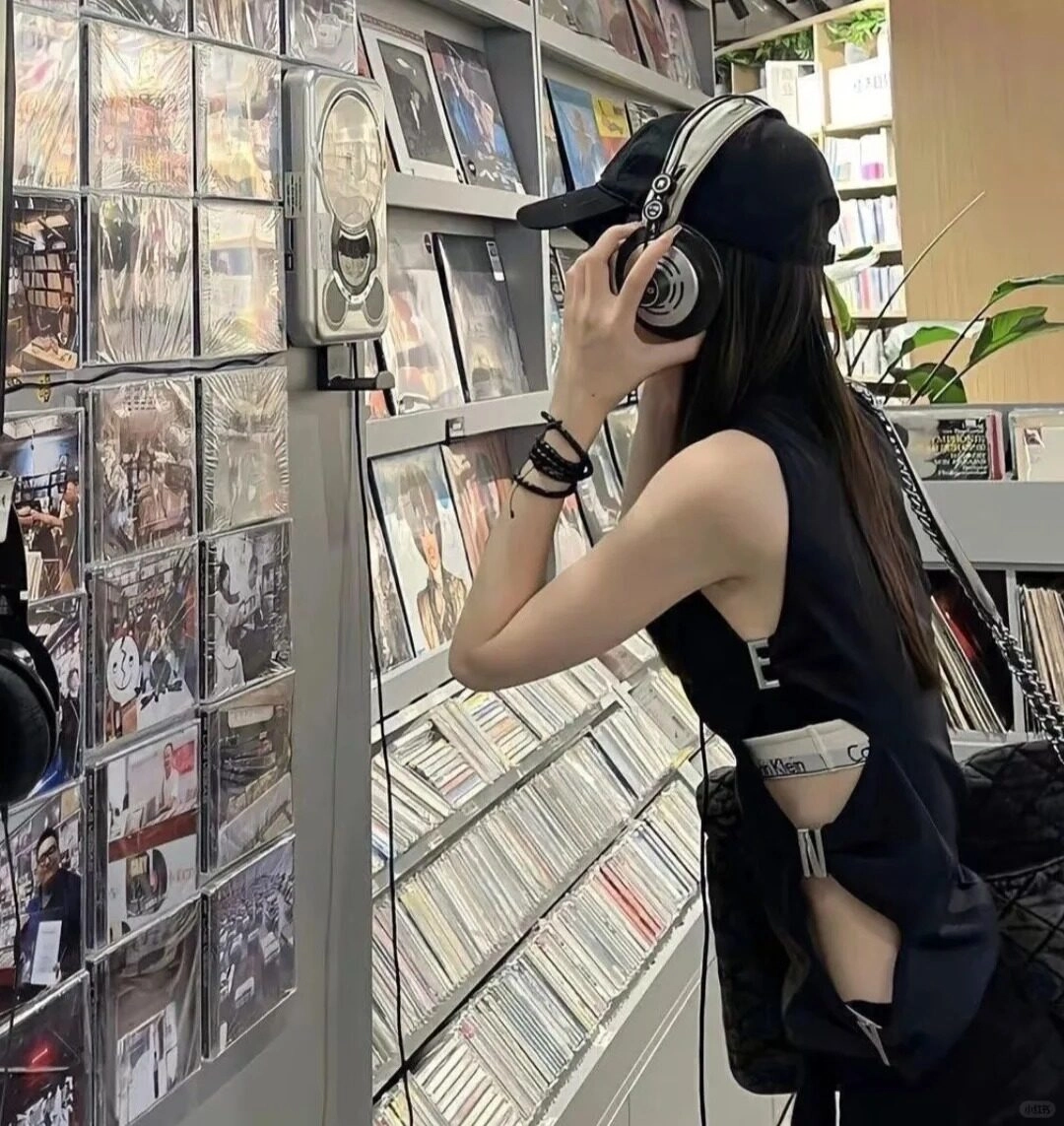 Bạn nữ cá tính đội mũ, đeo tai nghe trong cửa hàng đĩa nhạc.