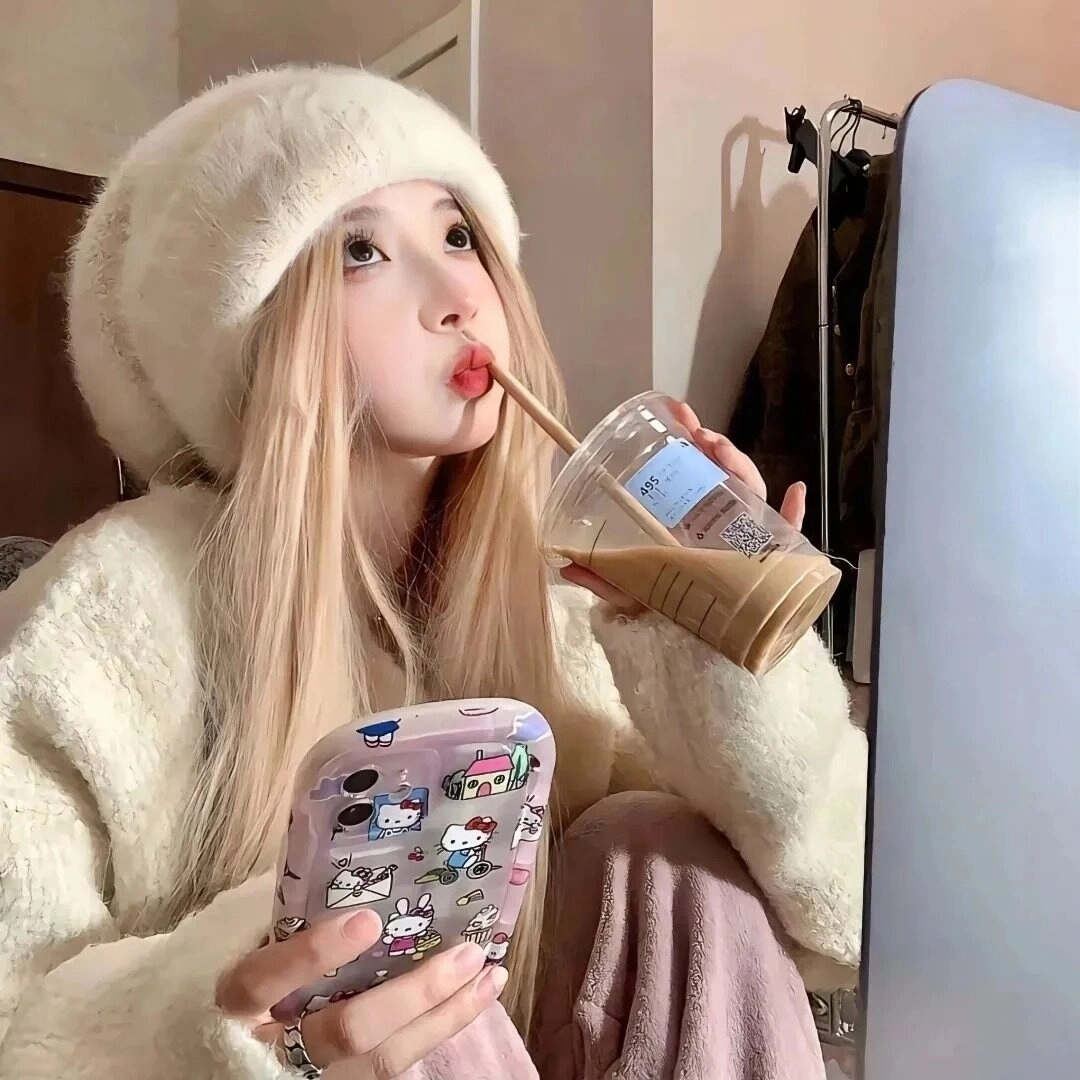 Cô gái với áo khoác và mũ len trắng tạo dáng đáng yêu khi uống caffe.