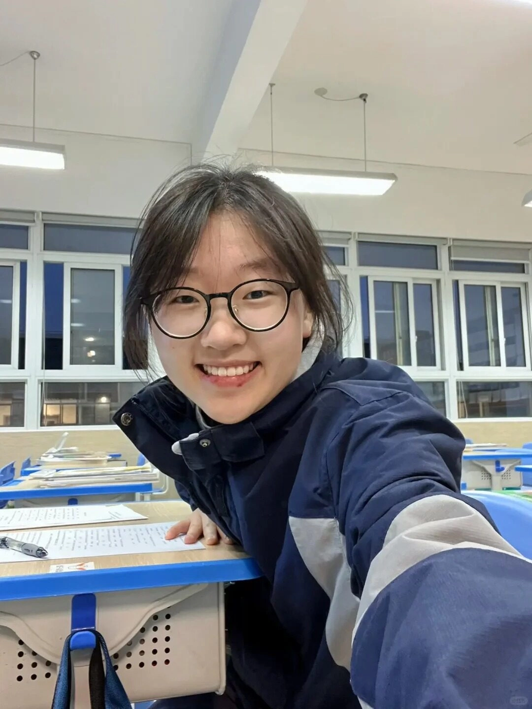 Gái xinh 2k9 đeo kính cận, nụ cười rạng rỡ trong lớp học. 