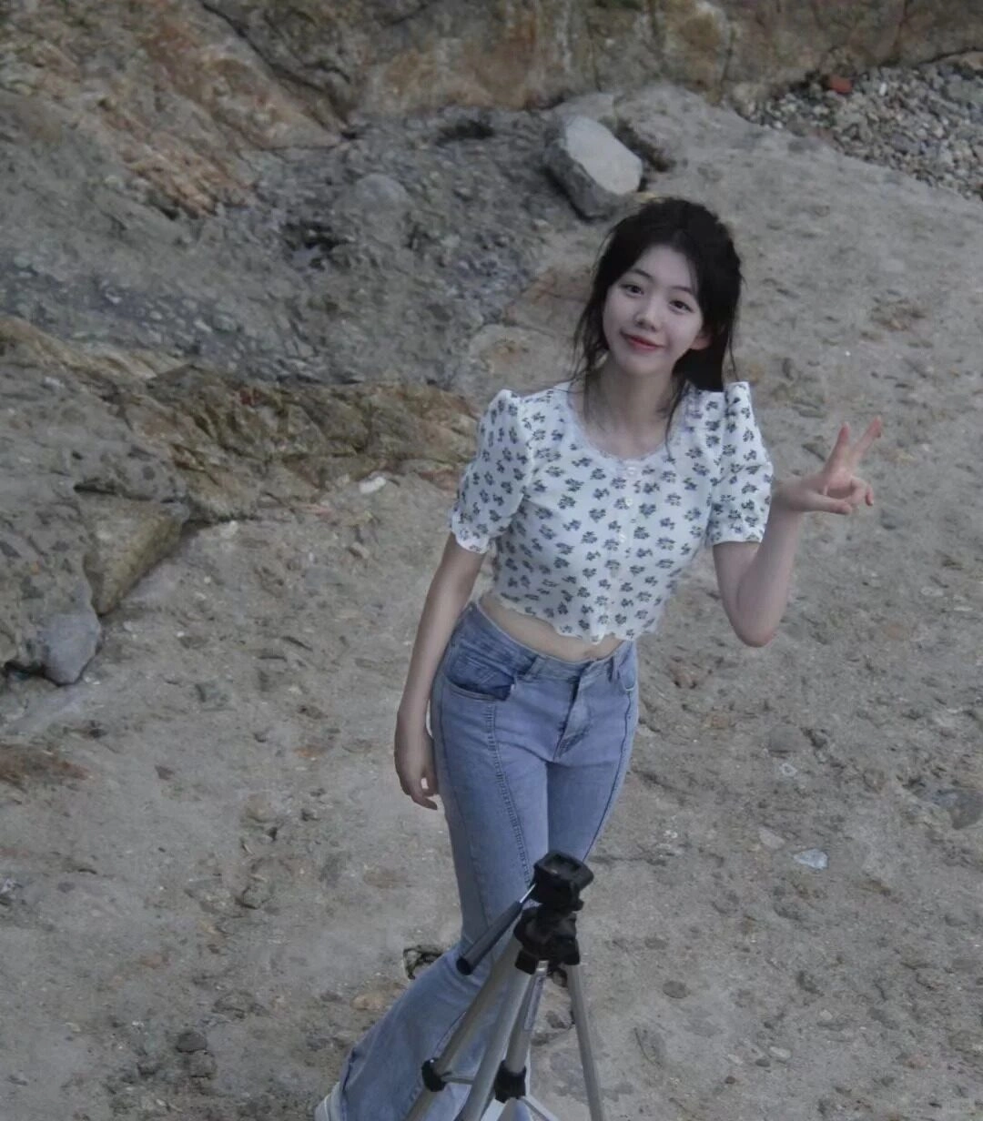 Cô gái tạo kiểu dáng với máy ảnh, áo crop top hoa nhí và quần jean trẻ trung.