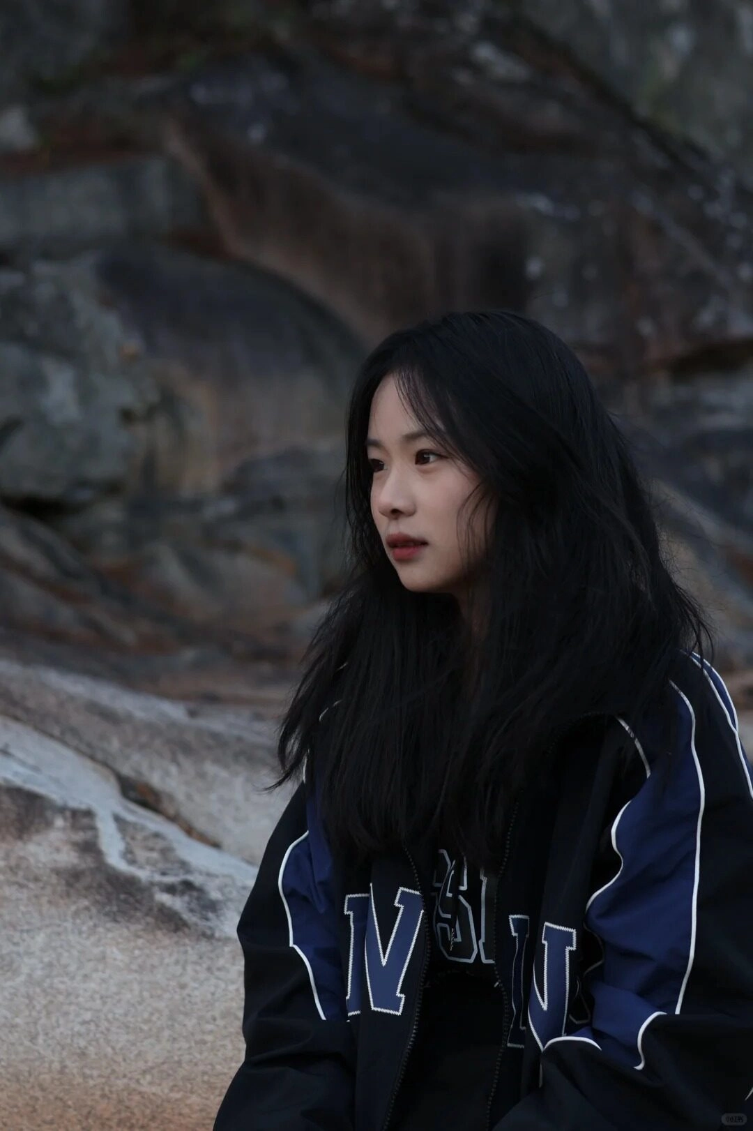 Thiếu áo khoác nữ thể thao cá tính, vẻ ngoài ưu tư cạnh bờ đá.