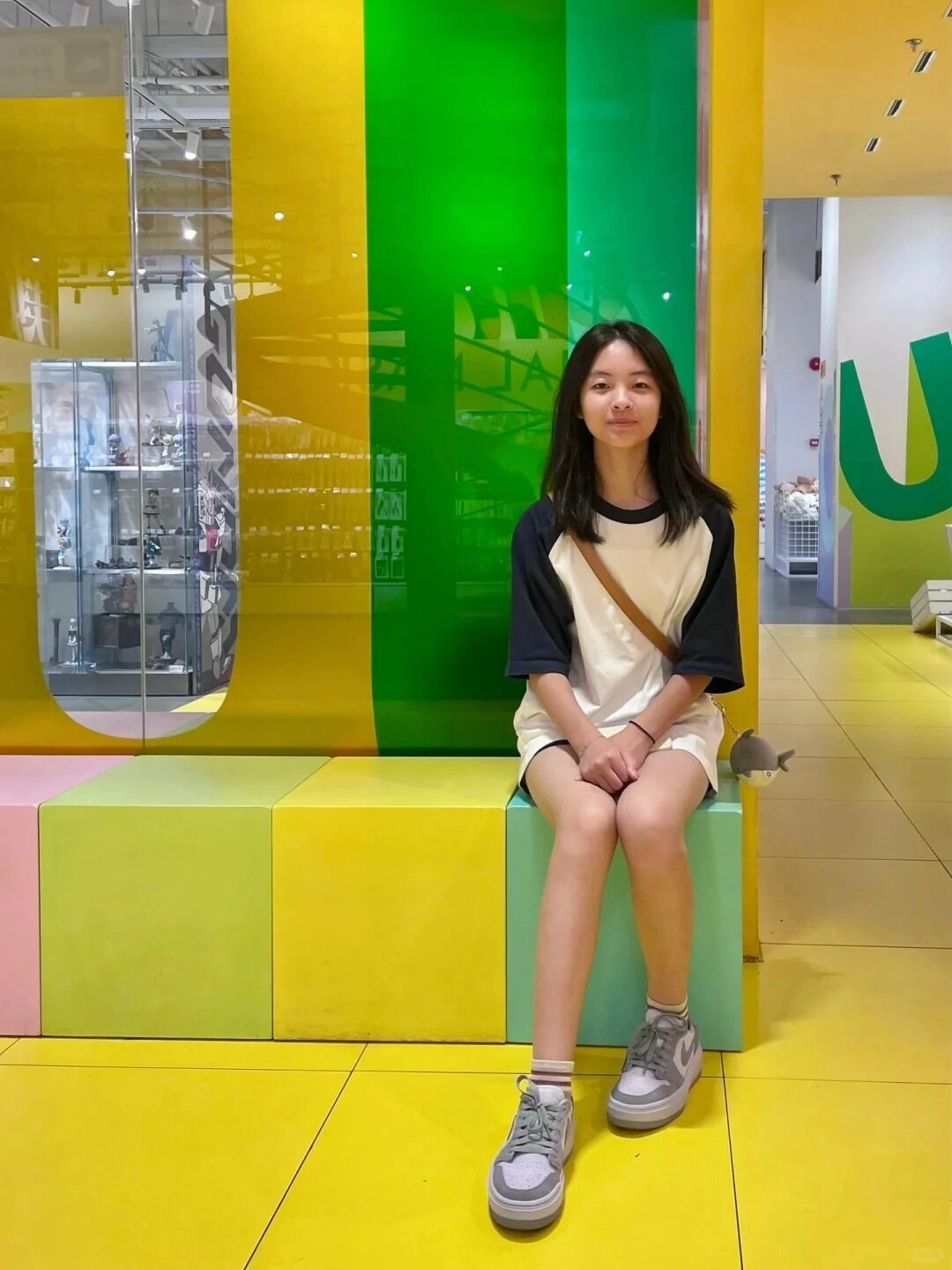 Thiếu nữ váy trắng phối đen, ngồi thư giãn trong cửa hàng màu sắc.