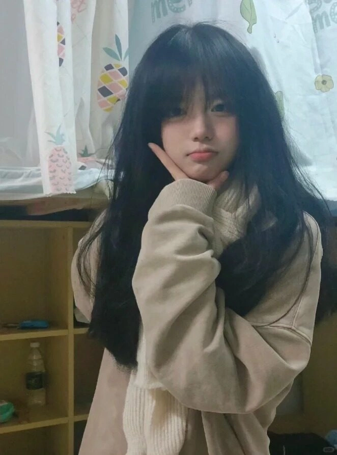 Cô gái áo hoodie rộng, tóc dài xoăn nhẹ, tạo kiểu dáng vừa vặn trong phòng.