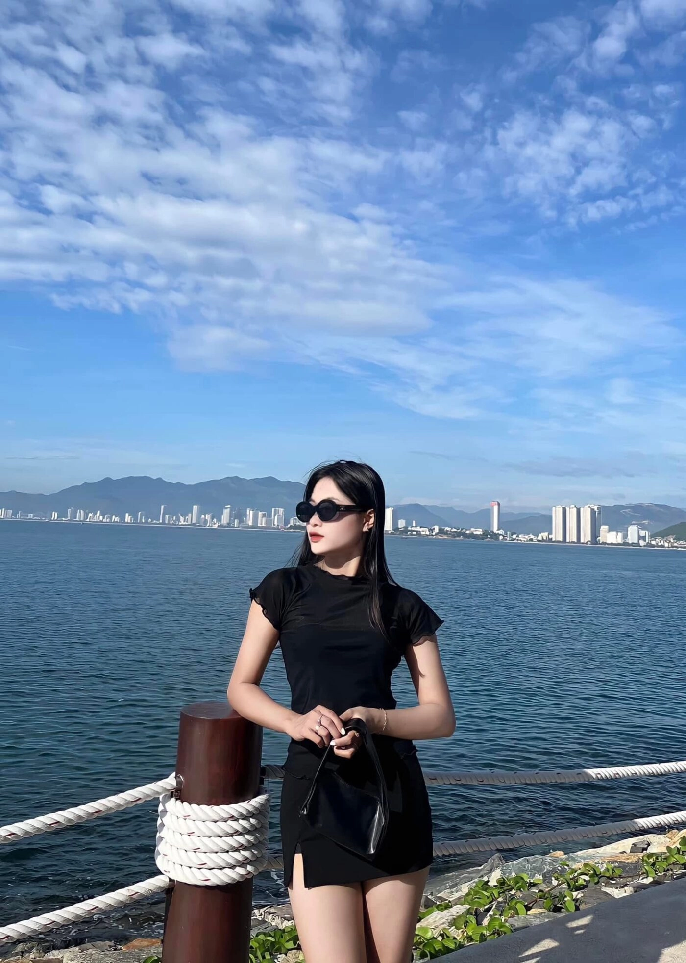 Đầm đen ôm dáng cá tính, tóc xõa dài, kính râm thời thượng.