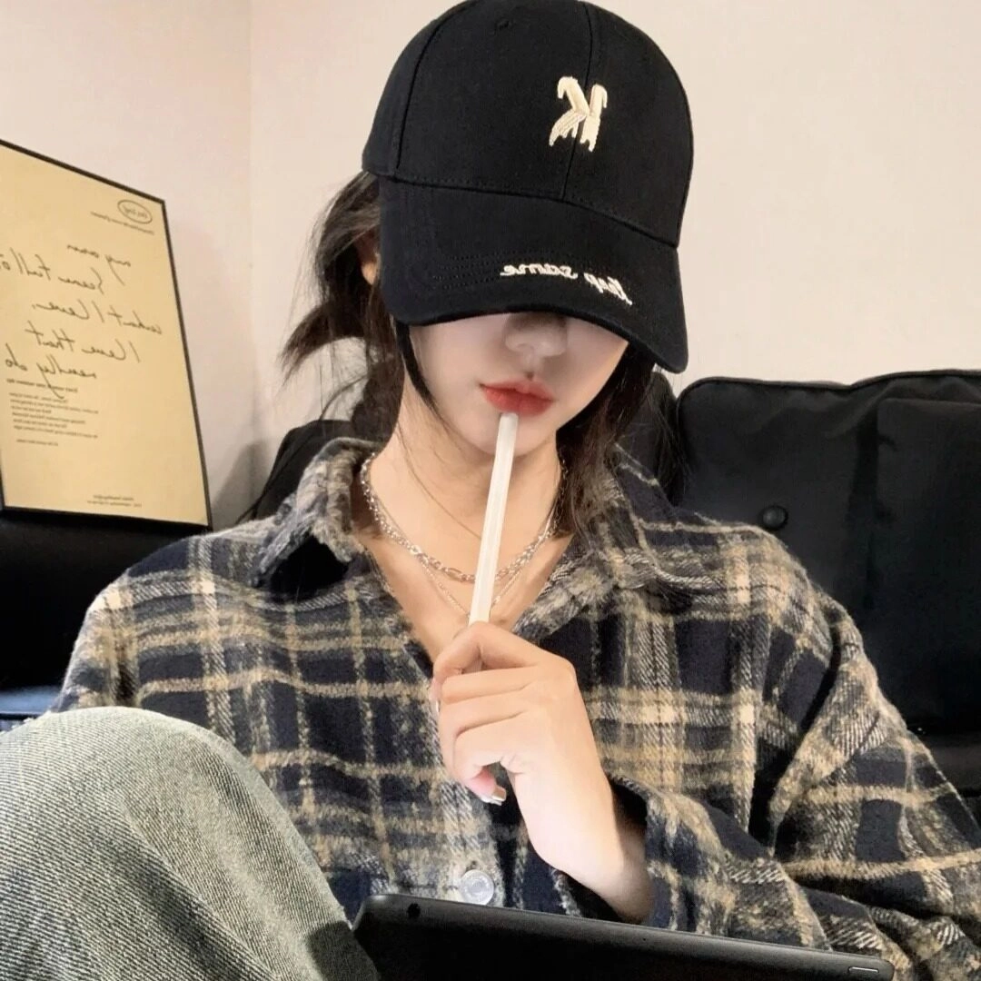 Đội mũ đen, cắn ống hút, diện áo sơ mi caro trong vibe thư giãn.