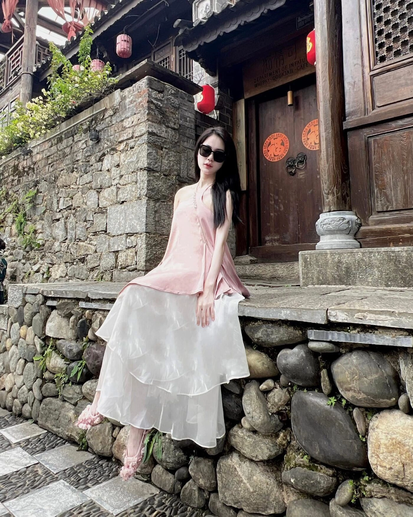 Thiếu nữ váy lụa hồng trắng bồng bềnh, ngồi tựa trên nền đá cổ kính