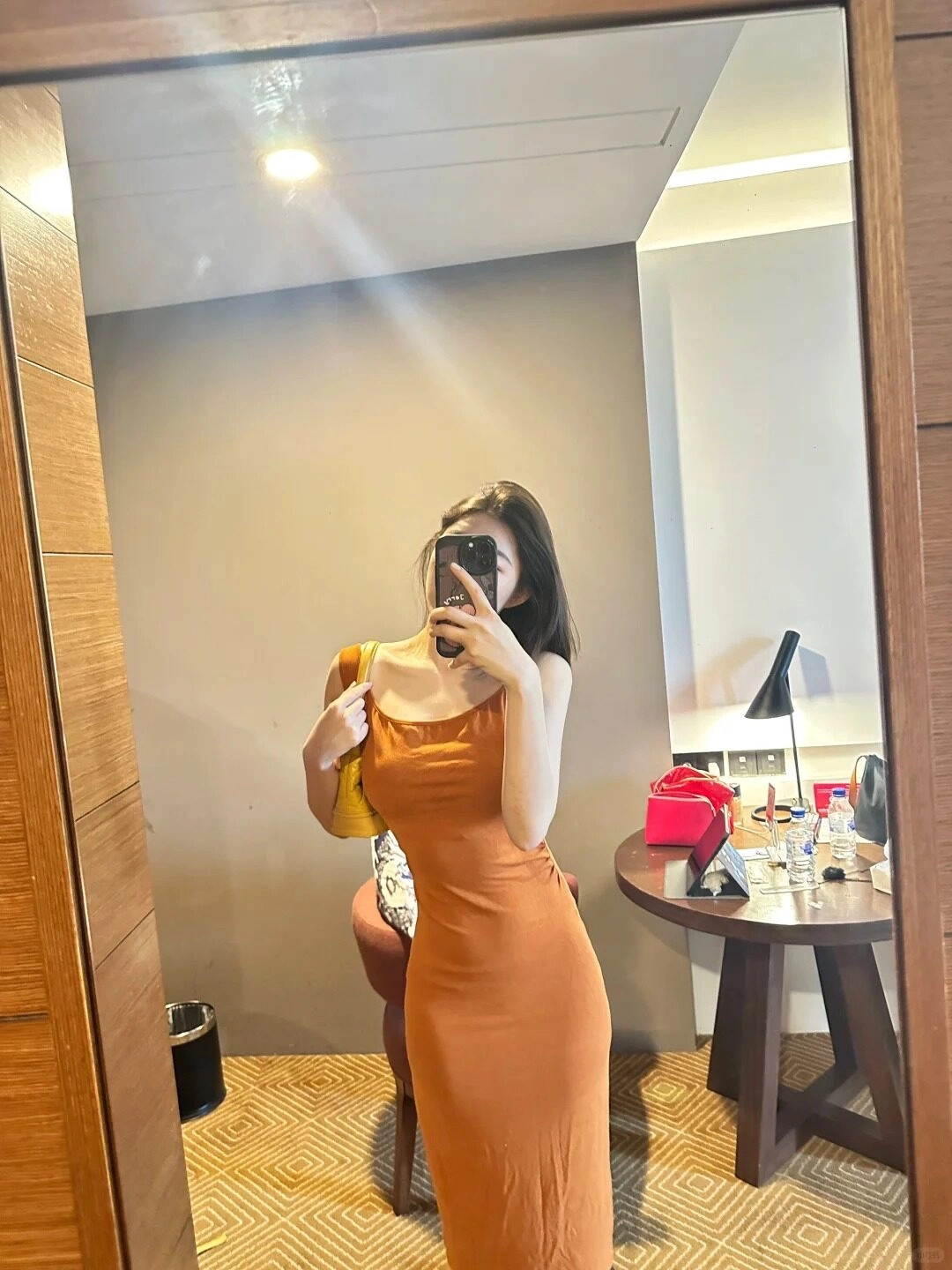 Cô gái tạo kiểu dáng quyến rũ, diện váy ôm cam nổi bật, chụp ảnh trước ống kính.