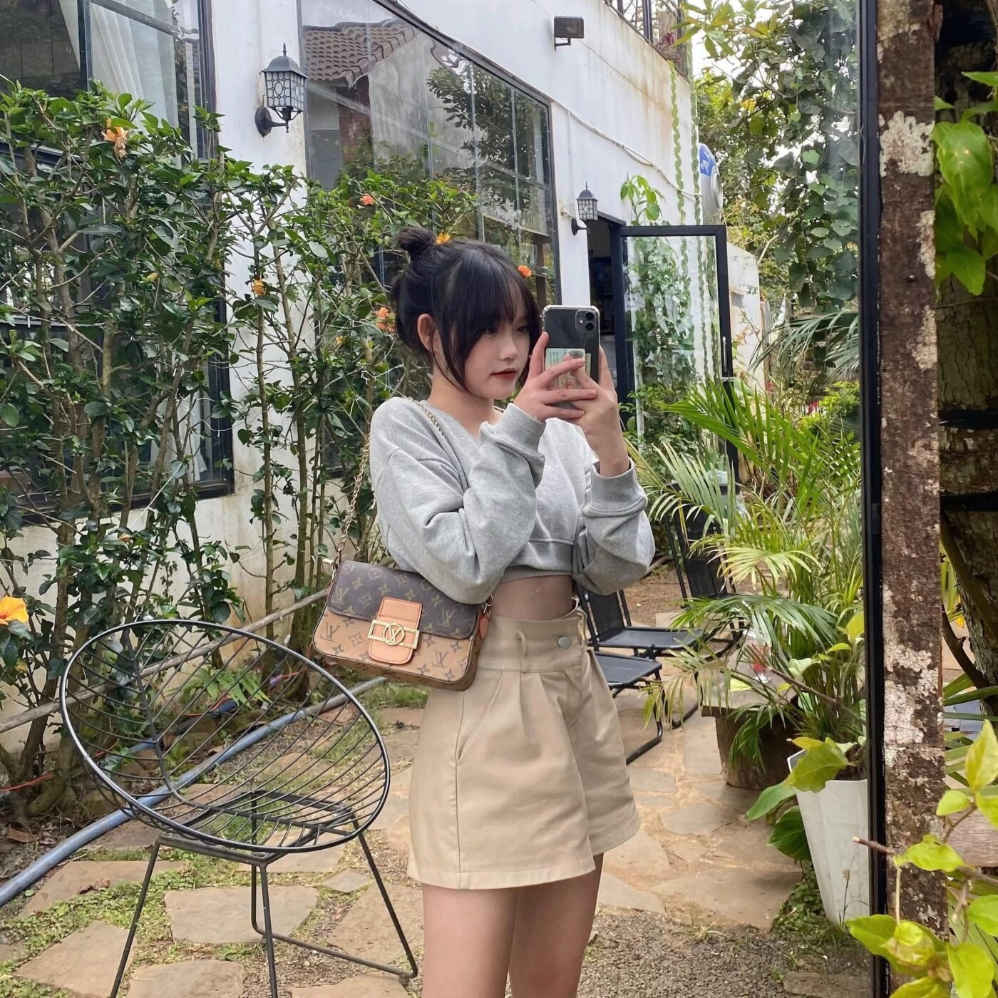 Tóc búi đôi dễ thương, áo croptop xám phối cùng chân váy be năng động.