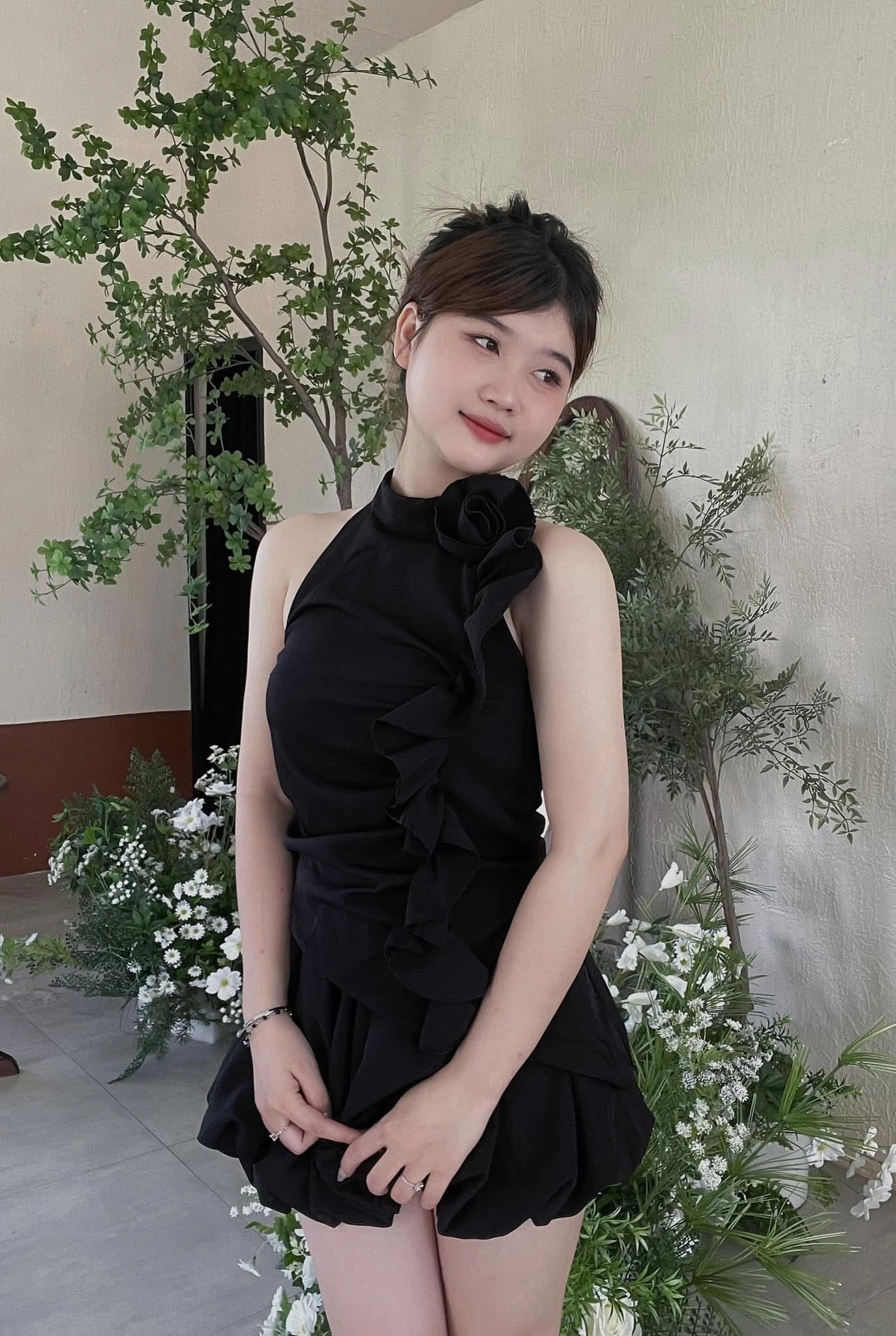 Váy đen ôm sát với điểm nhấn hoa lớn, tóc búi gọn nhẹ nhàng.